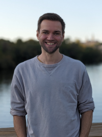 an image of Marcel in front of a body of water with forest in the background