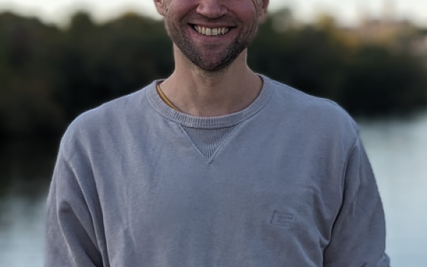 an image of Marcel in front of a body of water with forest in the background