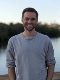 an image of Marcel in front of a body of water with forest in the background